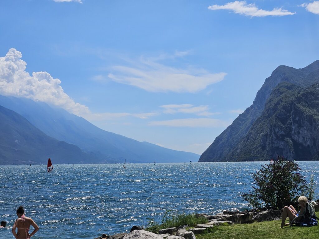 Szeroki kadr na jezioro Garda z widokiem na góry i windsurferów
