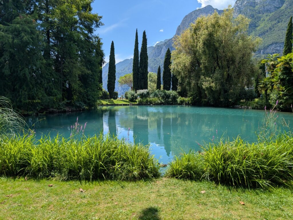 Park ze stawem i cyprysami na tle gór
