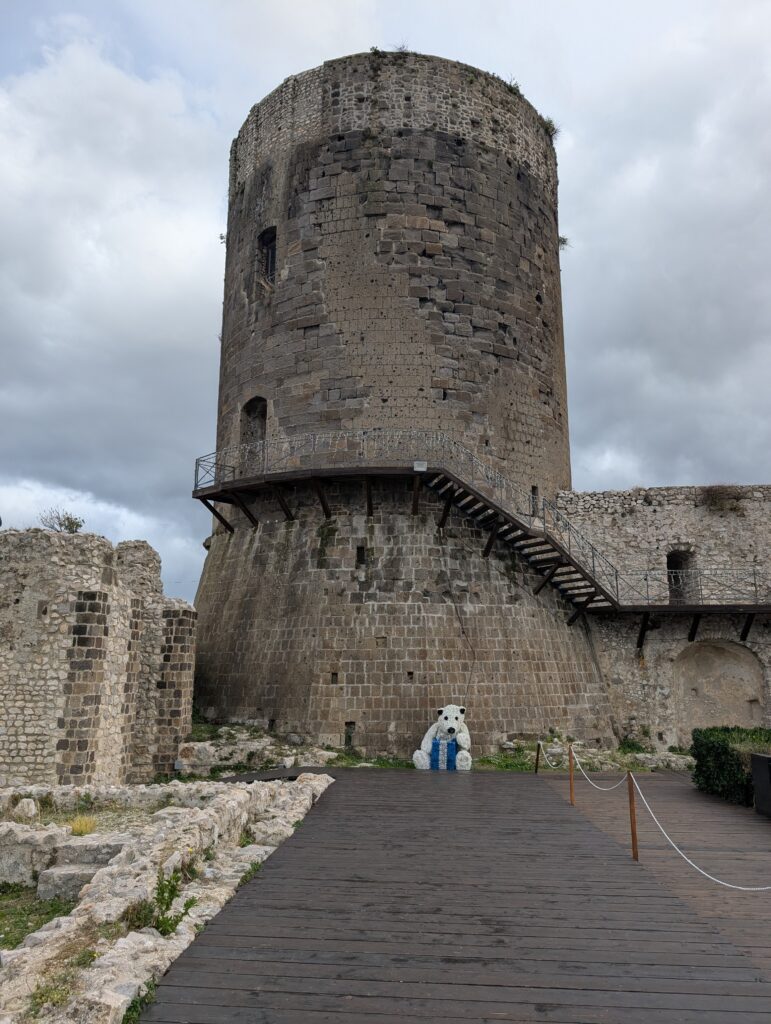 Kamienna wieża zamku Castello di Lettere z dekoracją świąteczną w kształcie białego misia.