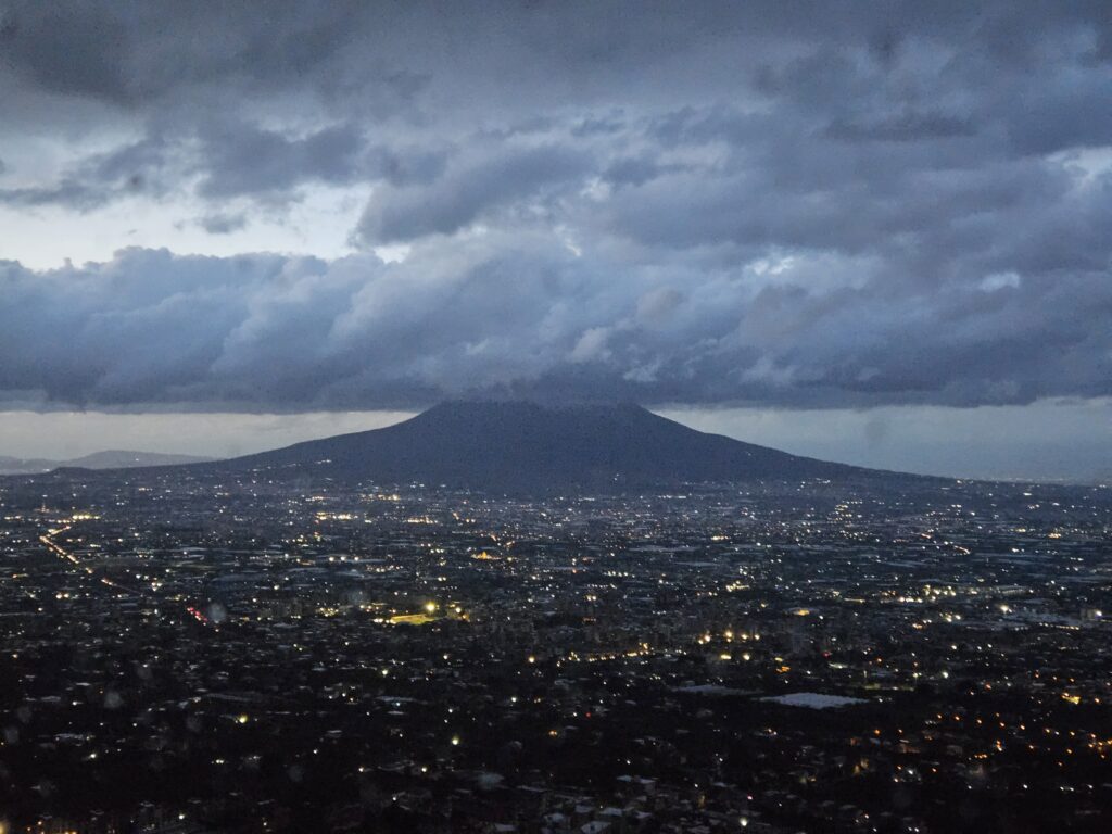 Nocna panorama miasta i Wezuwiusza widziana z górskiej drogi.