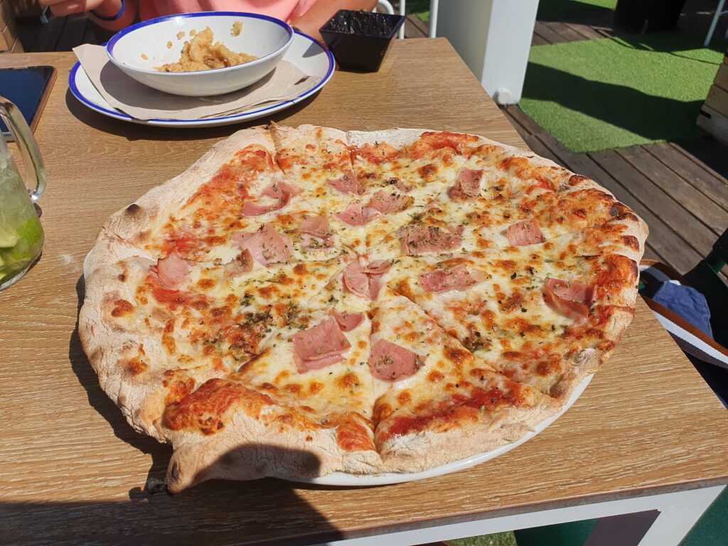 Duża pizza na drewnianym stole w restauracji BNS Street Food