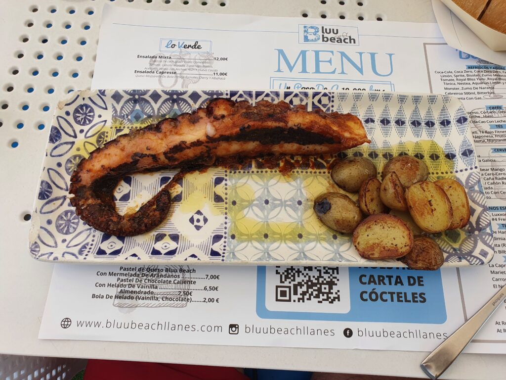Grillowana macka ośmiornicy z ziemniakami na talerzu we wzory