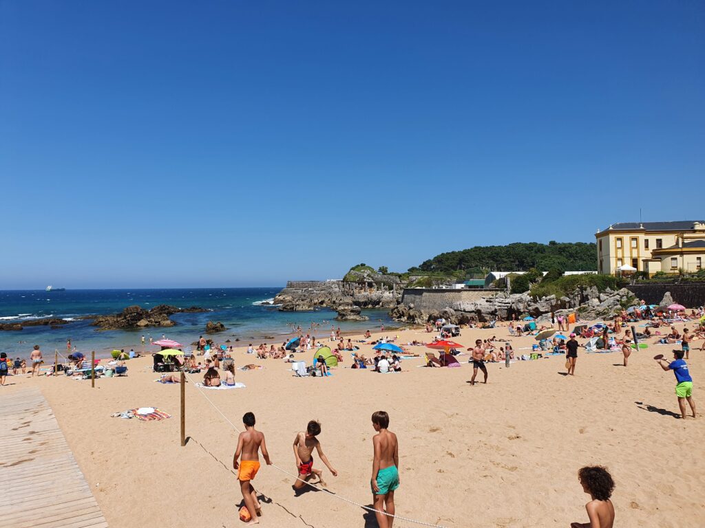 Plaża del Camello w Santander, ludzie grający w piłkę, w tle skała wielbłąda