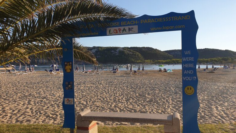 Szeroka, piaszczysta Rajska Plaża w miejscowości Lopar na wyspie Rab, widok na płytką zatokę i góry.