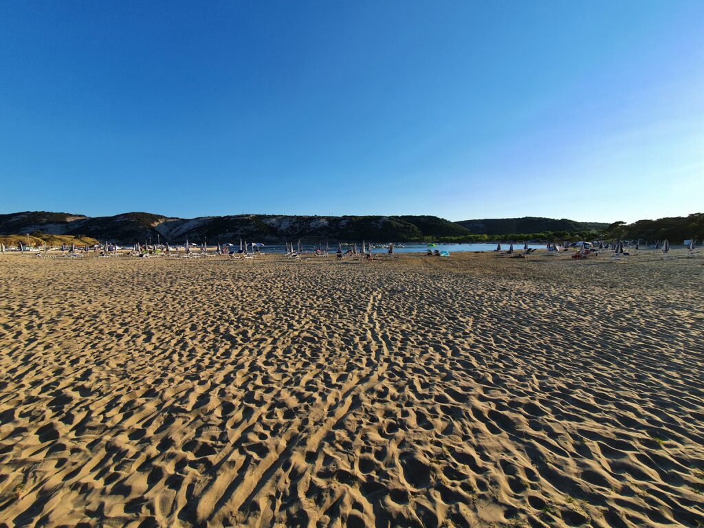 Szeroka panorama Rajskiej Plaży w Lopar z setkami parasoli pod koniec dnia