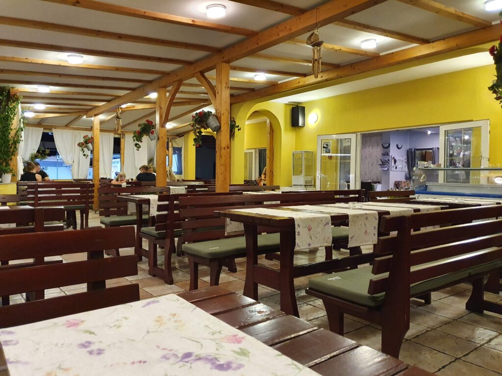 Wnętrze restauracji Navigator w Lopar z drewnianymi ławami i żółtymi ścianami