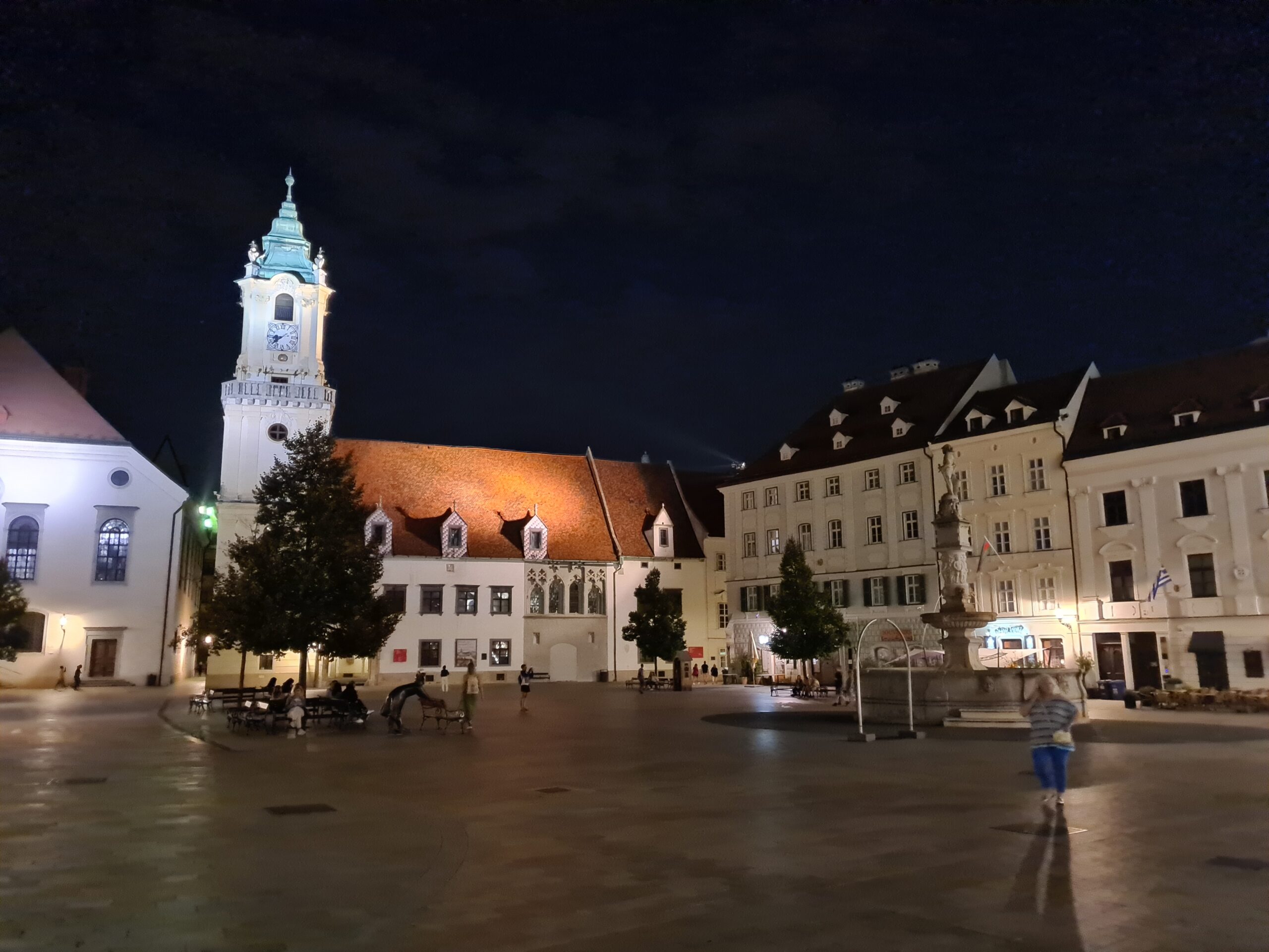 Rynek Główny w Bratysławie nocą z widokiem na Ratusz i fontannę Rolanda.