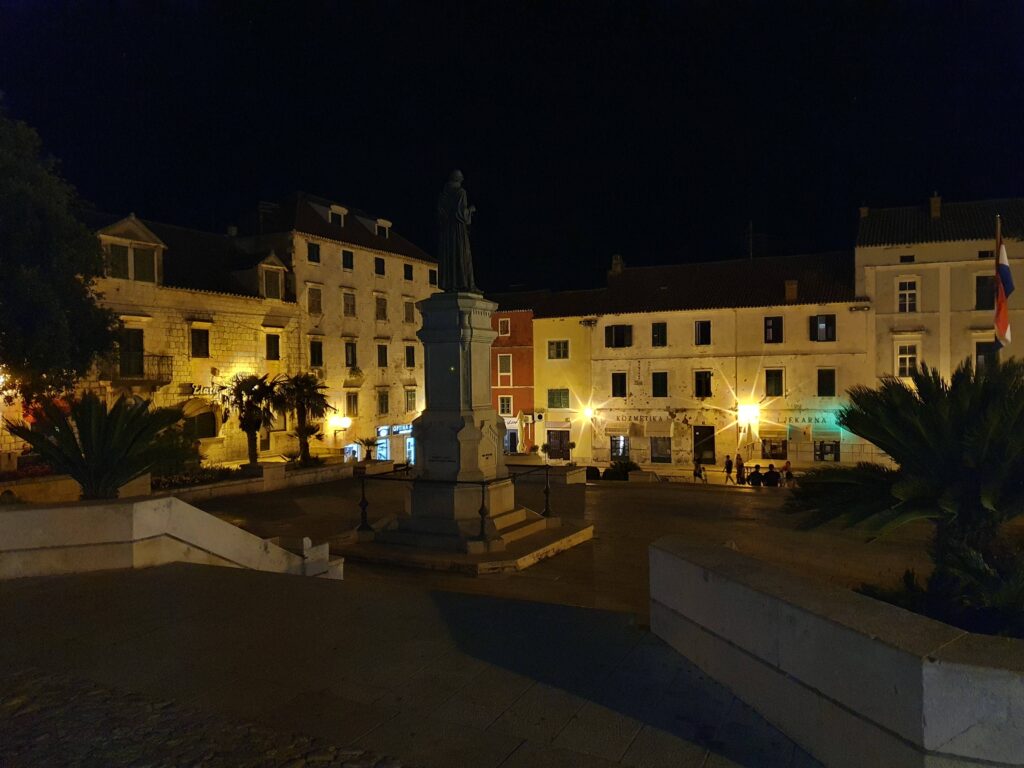 Makarska nocą, statua i oświetlone budynki