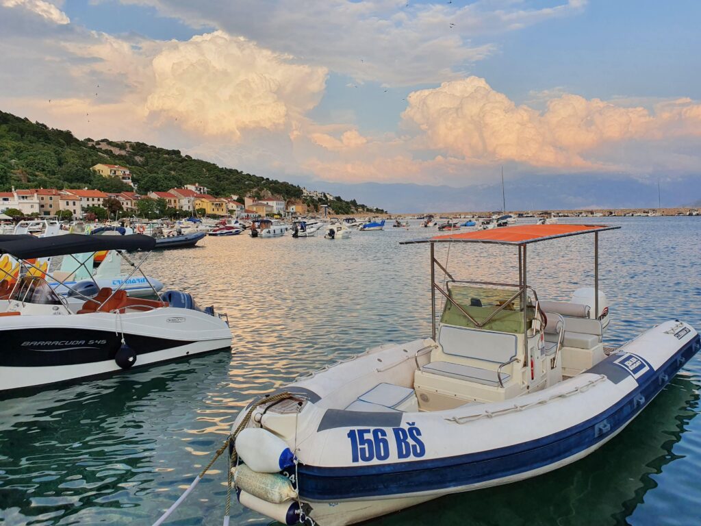 Port w Bašce z łodziami na tle gór i zachodzącego słońca