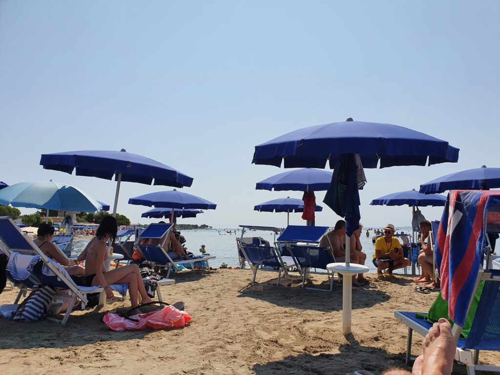 Piaszczysta plaża Bijeca w Medulinie z rzędami parasoli i ludźmi w wodzie