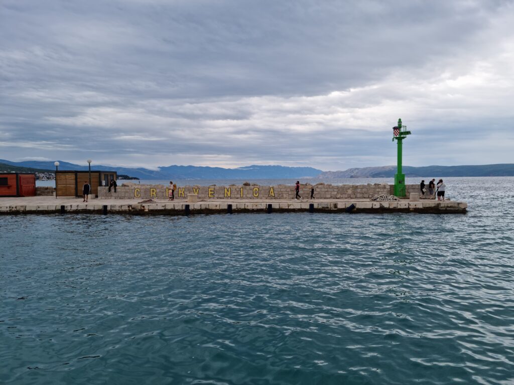 Żółty napis Crikvenica na betonowym falochronie w porcie