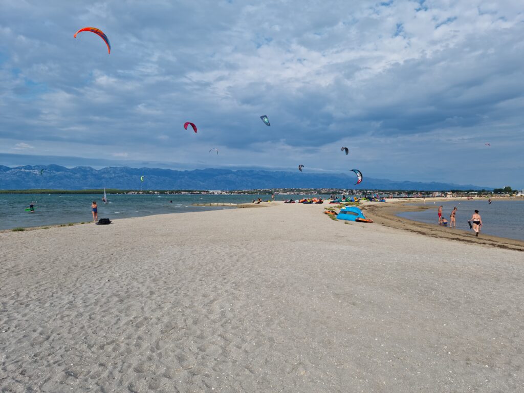 Kitesurferzy na plaży w Ninie na tle gór