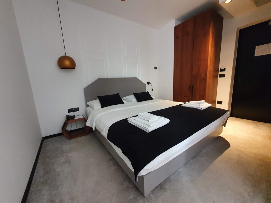 Duże podwójne łóżko w jasnym, nowoczesnym pokoju Hotelu Delfin w Rovinj
