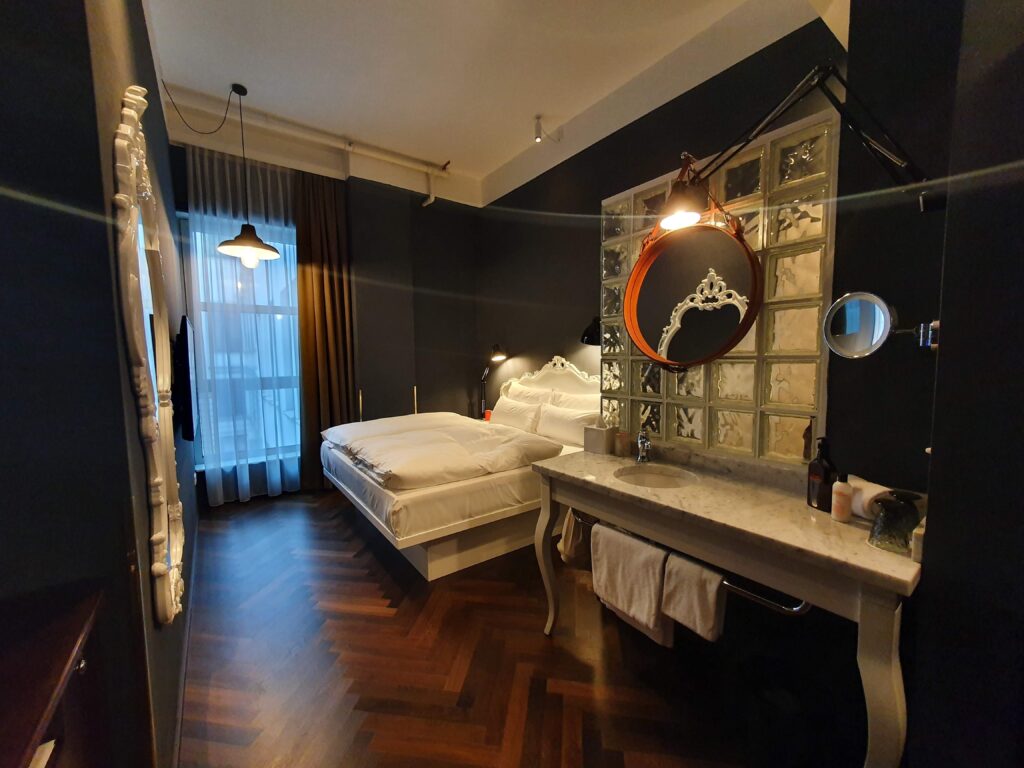 Eleganckie łóżko małżeńskie i marmurowa umywalka w pokoju Hotel Grand Ferdinand Wien