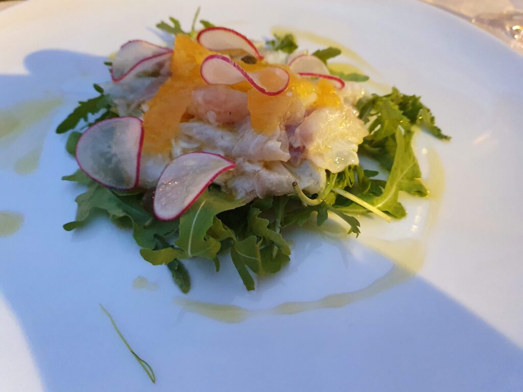 Przystawka z surowych ryb i cytrusów na liściach rukoli w restauracji Pierino