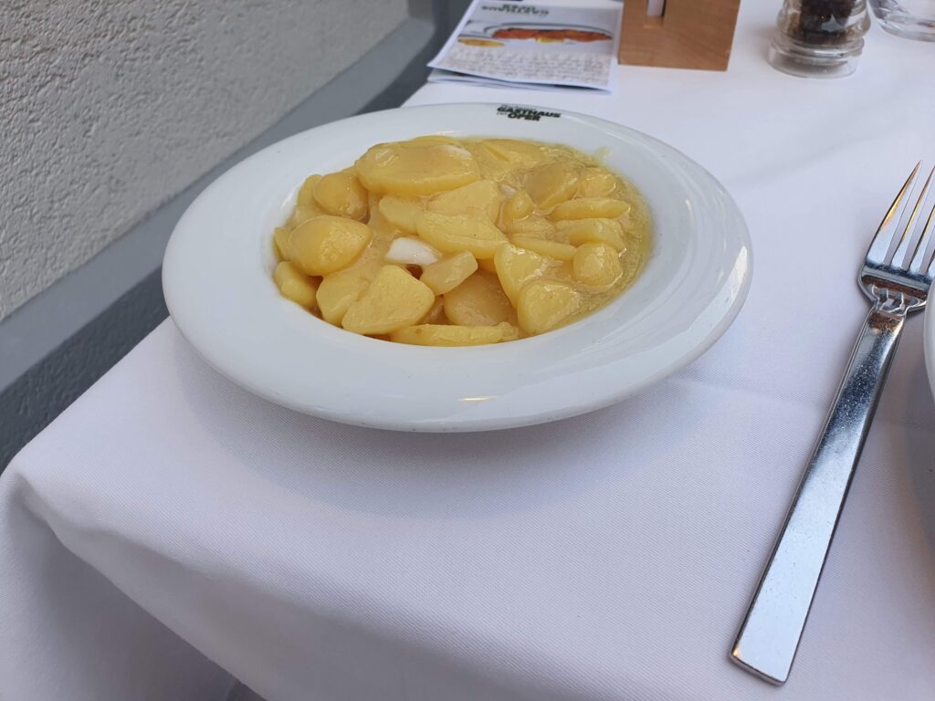 Tradycyjna wiedeńska sałatka ziemniaczana podana w głębokim talerzu w restauracji Plachutta