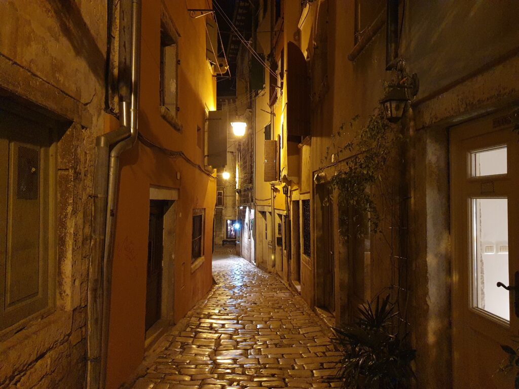 Wąska, stroma, wybrukowana uliczka w Rovinj nocą