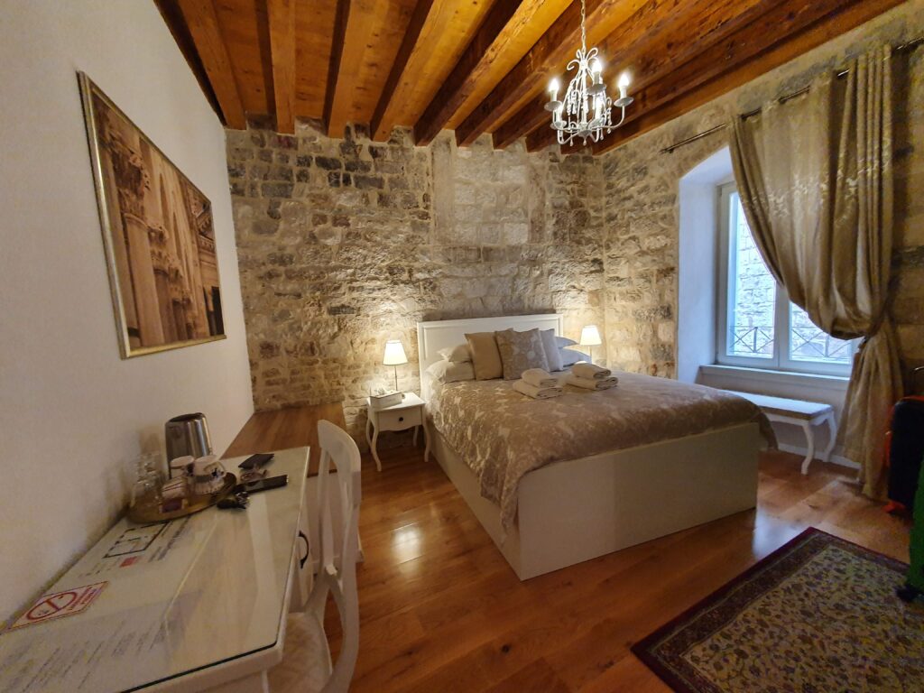 Wnętrze pokoju w Villa Split Heritage Hotel z surową kamienną ścianą