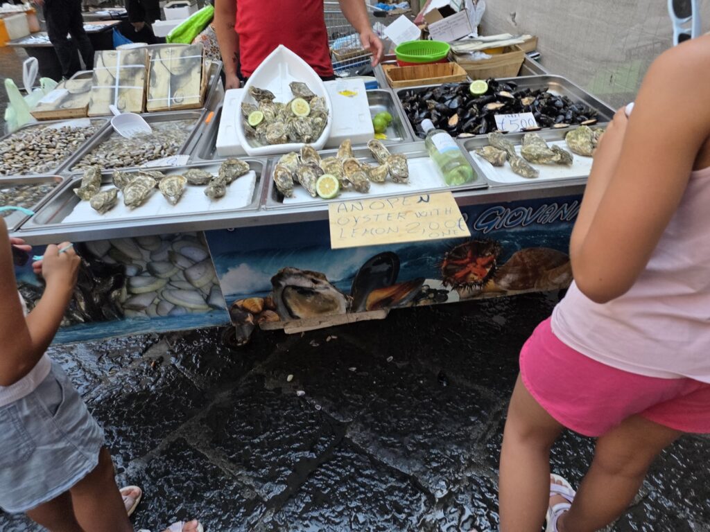Świeże ostrygi z cytryną sprzedawane na wózku na targu rybnym w cenie 2 euro za sztukę