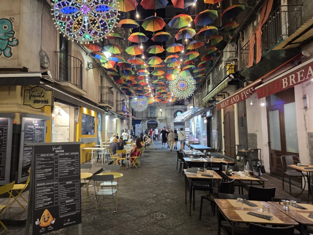 Gwarne stoliki restauracji Vuciata ustawione na ulicy pod dachem z setek kolorowych parasoli