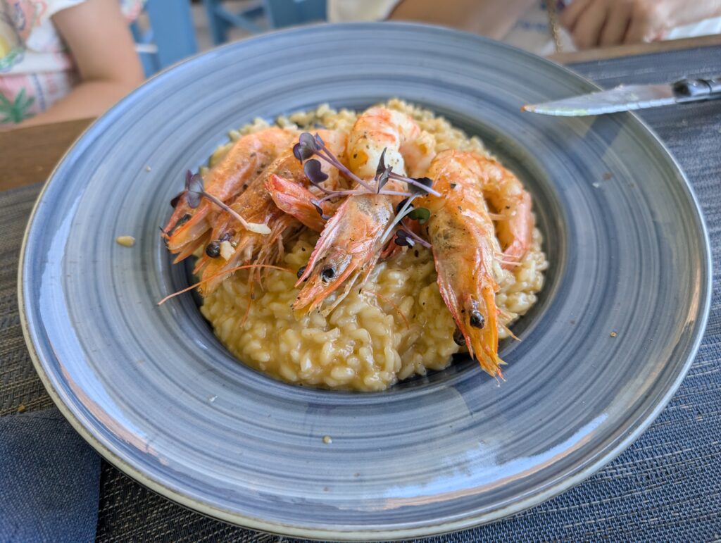 Kremowe risotto z szafranem podane z pięcioma całymi, grillowanymi krewetkami w pancerzach