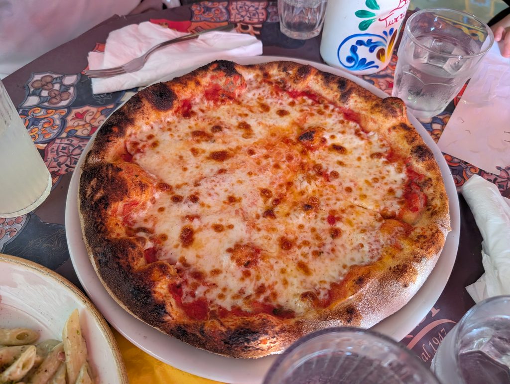 Pizza margherita z przypieczonym brzegiem na białym talerzu