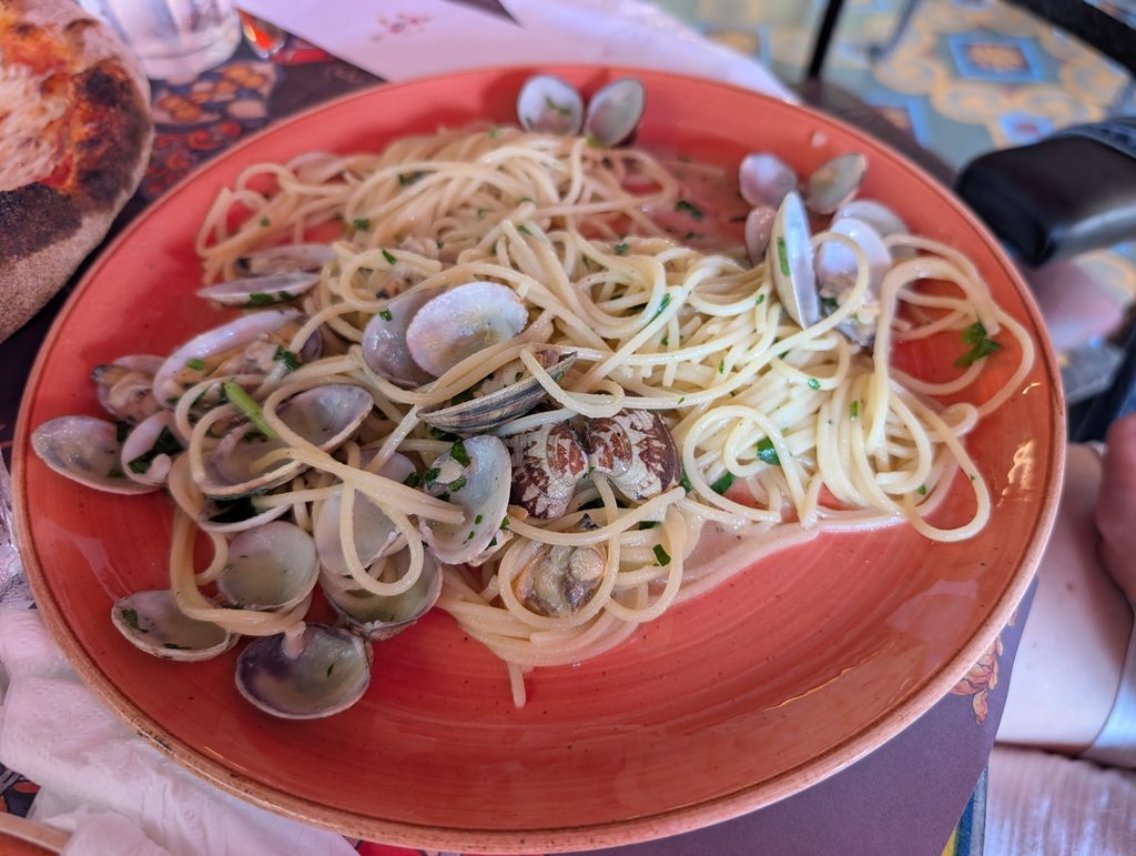 Spaghetti z małżami vongole na pomarańczowym talerzu w Bar Turrisi